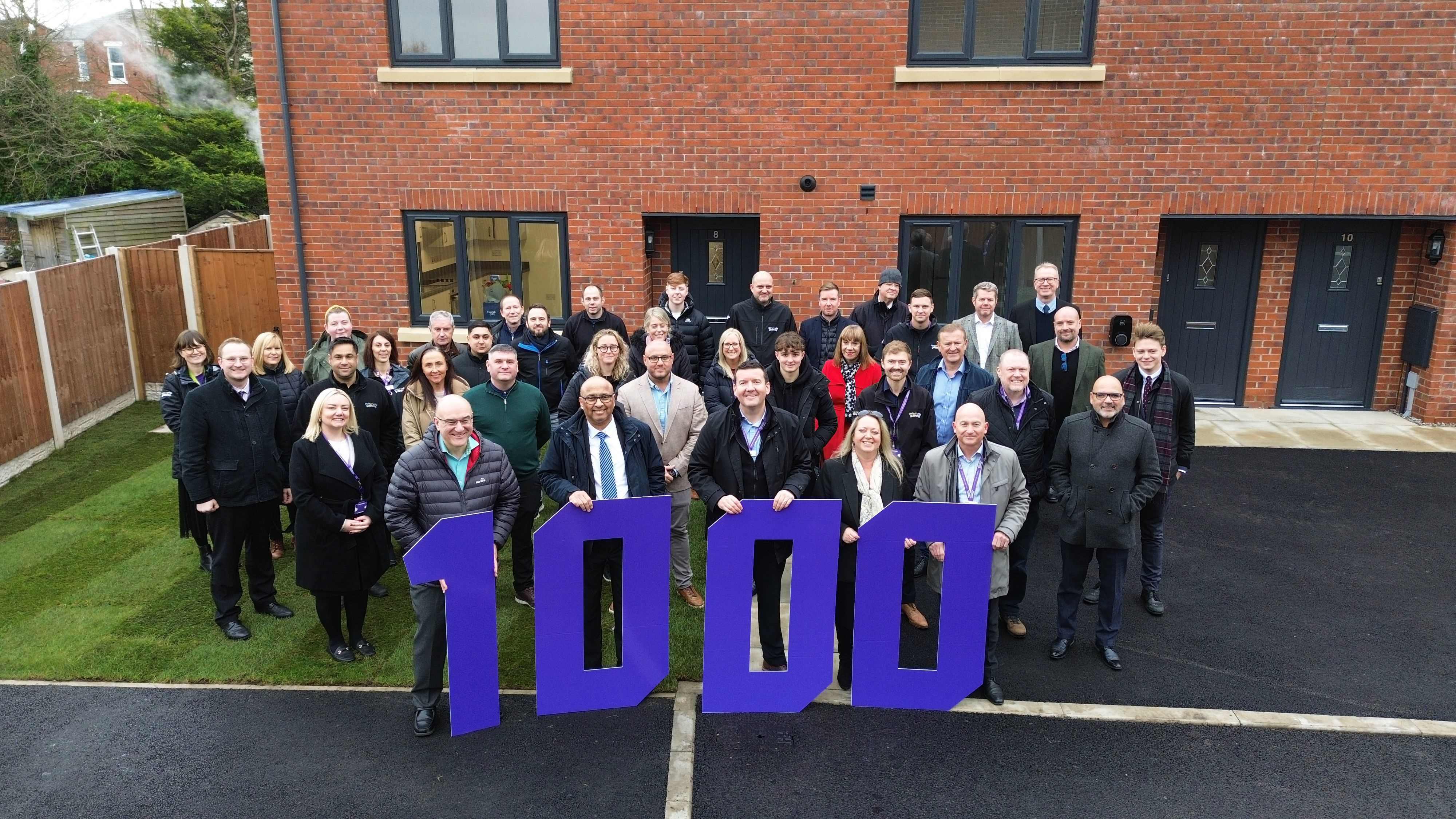 A large group of people in front of large purple numbers showing one thousand