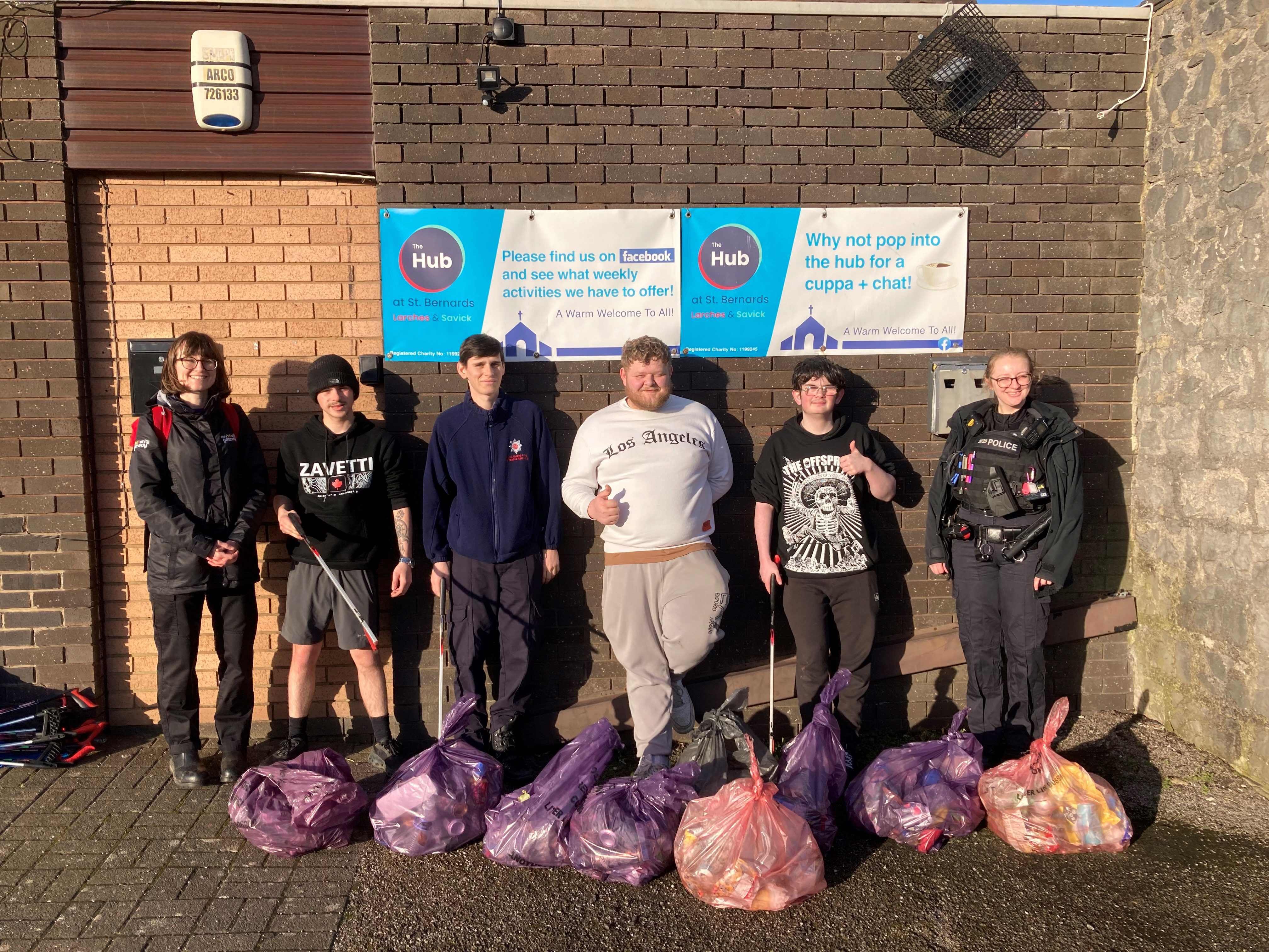 A group of people with full bags of litter and litter picking equipment